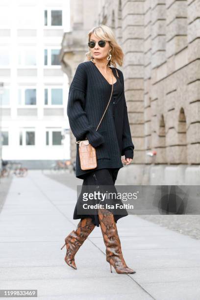 Influencer Gitta Banko is wearing an oversized black wool cardigan and a black wool skirt by Boscana x Gitta Banko, a black ribbed tanktop by Zara,...