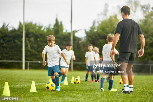 preteen spanish footballers doing dribbling drills on field - cone de trânsito imagens e fotografias de stock