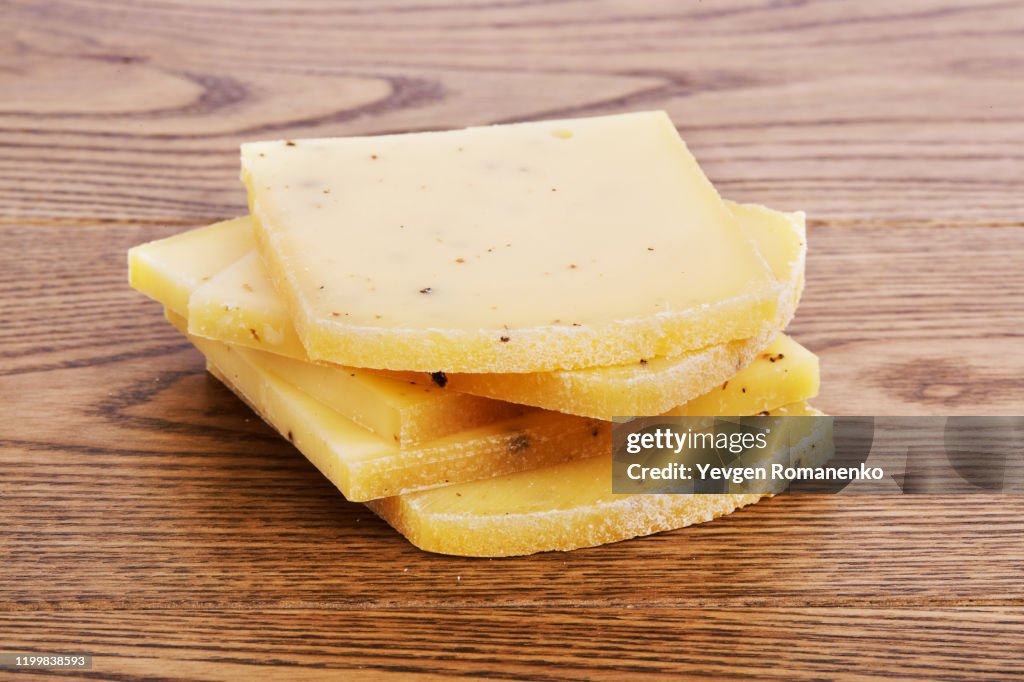 Slices of Raclette cheese with truffle on a wooden background