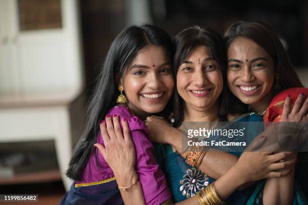 portrait of an indian mother embracing her daughters - traditional festival imagens e fotografias de stock