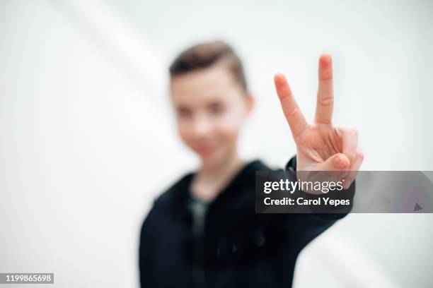 cool blonde boy  showing sign peace with hands - gesto de victoria fotografías e imágenes de stock