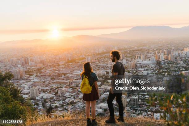 mulher e homem que estão e que olham santiago no por do sol - santiago região metropolitana de santiago - fotografias e filmes do acervo