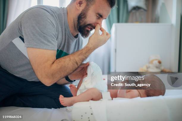 vater wechselt windel auf seinem kleinen jungen zu hause - changing diaper stock-fotos und bilder