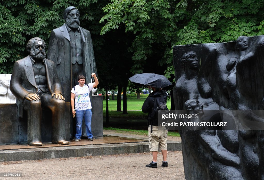A man poses in front of a bronze statue