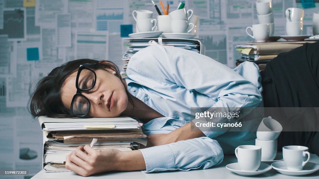 Exhausted businesswoman lying down on the desk and sleeping