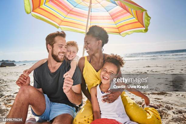 family on beach - yellow umbrella stock pictures, royalty-free photos & images