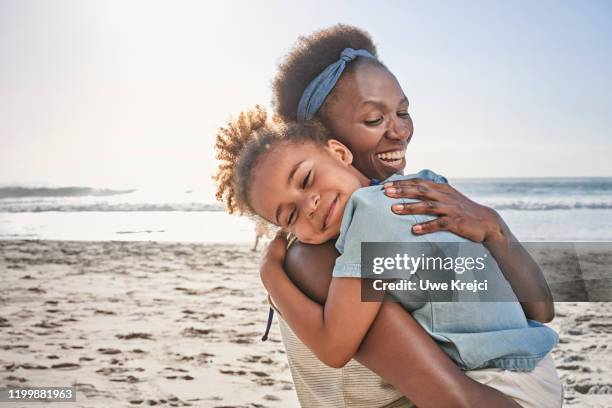 mother and daughter on beach - familie schutz stock-fotos und bilder