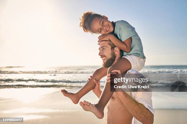 young man carrying girl on shoulder on beach - female hairy chest stock-fotos und bilder