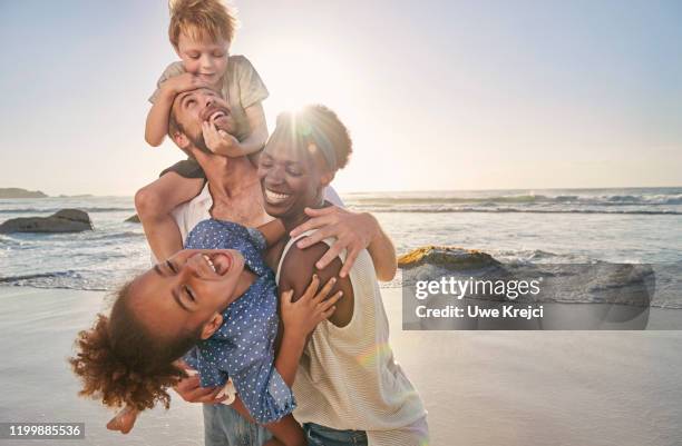 family playing on beach - mixed race family fotografías e imágenes de stock