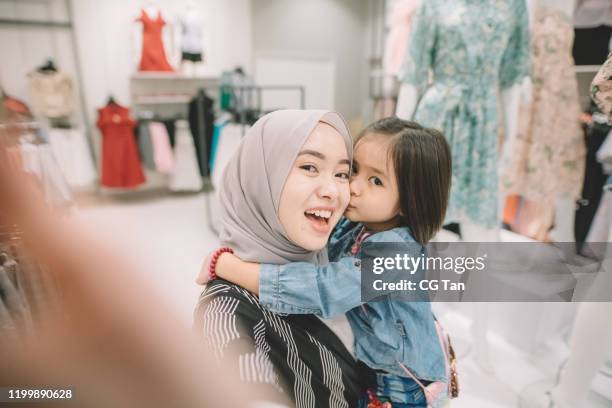 an asian malay young woman shopping in a boutique shop with her daughter taking selfie - malay people stock pictures, royalty-free photos & images