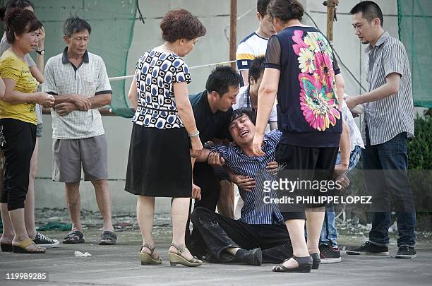 Chen Shengqiao , who lost his 12-year-old daughter Chen Yijie in the train accident, is helped by relatives as he cries after identifying her body at...
