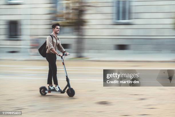 businessman riding scooter in the city - push scooter stock pictures, royalty-free photos & images