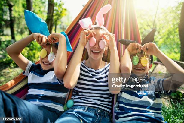 three kids playing with easter eggs found in the back yard - easter stock pictures, royalty-free photos & images