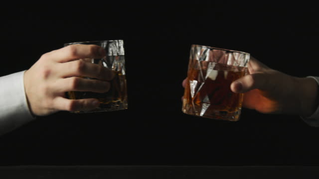 Two people makes a toast with whiskey