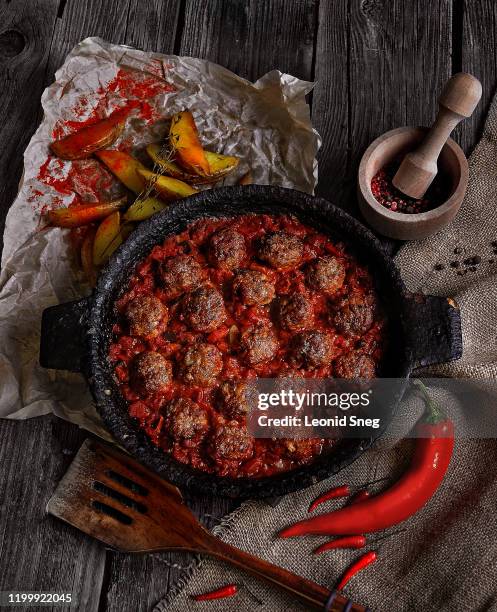 mitballs in spicy tomato sauce with baked potatoes in a rustic style on a wooden table top view - meatball stock pictures, royalty-free photos & images