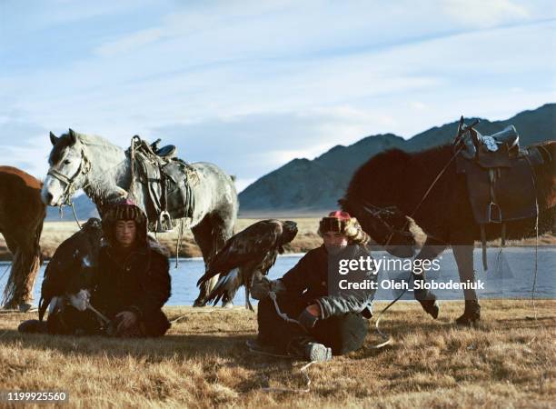portret van de groep van eagle hunters in de buurt van de rivier in mongolië - mongoolse etniciteit stockfoto's en -beelden