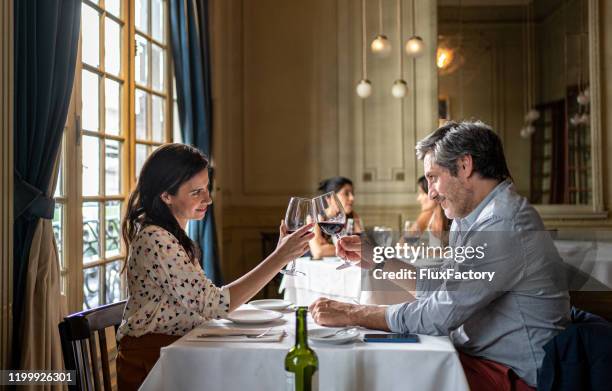 festeggiare la coppia facendo un brindisi celebrativo in un ristorante - valentines day dinner foto e immagini stock