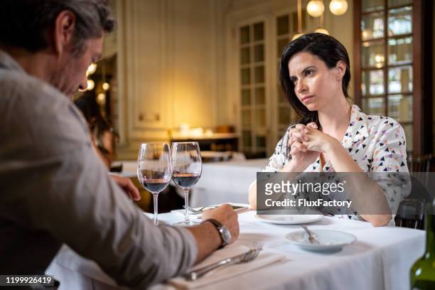 angry woman looking seriously at her man at a restaurant - angry girlfriend stock pictures, royalty-free photos & images
