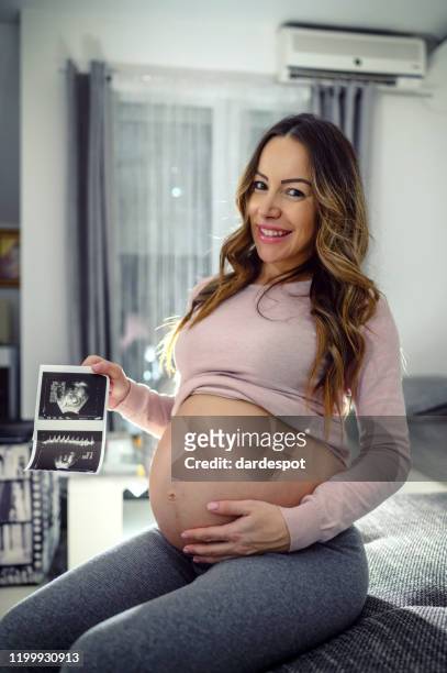 happy pregnant woman with ultrasound image at home - ivf stock pictures, royalty-free photos & images