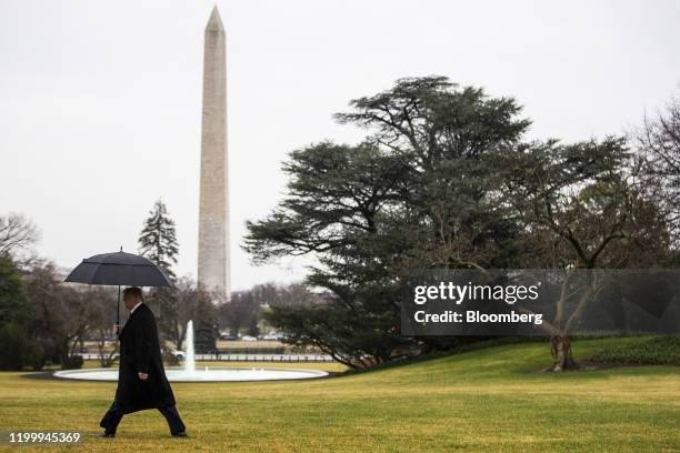 President Donald Trump carries an umbrella while walking on the South Lawn of the White House to board Marine One in Washington, D.C., U.S., on...