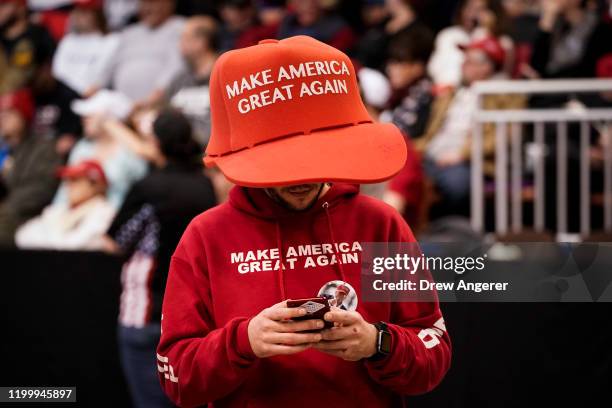 Supporter of U.S. President Donald Trump wears an oversize "Make America Great Again Hat" as he waits for the start of a "Keep America Great" rally...