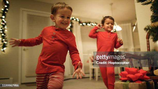 two young (three and five year-old) caucasian boys in pajamas run to the christmas tree excitedly on christmas morning - excited children imagens e fotografias de stock