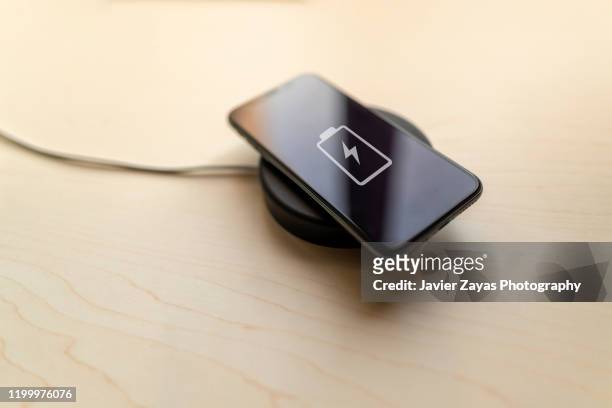 charging mobile phone with wireless charging device - drahtlose technologie stock-fotos und bilder