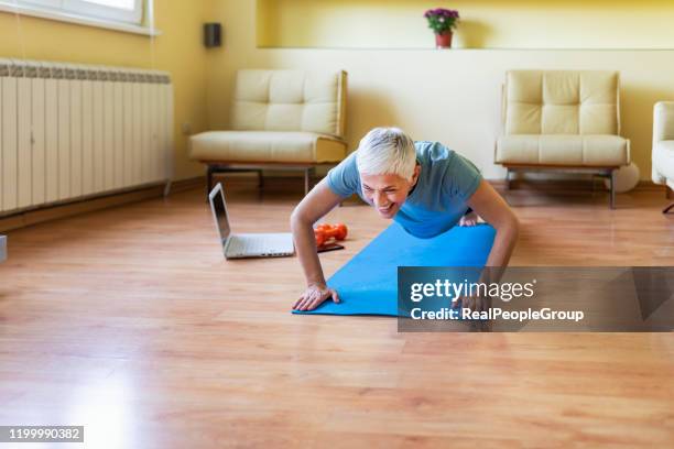 happy woman in her 50s stretching for exercise at home. joy of life and freedom in movement, concept. - core strength stock pictures, royalty-free photos & images