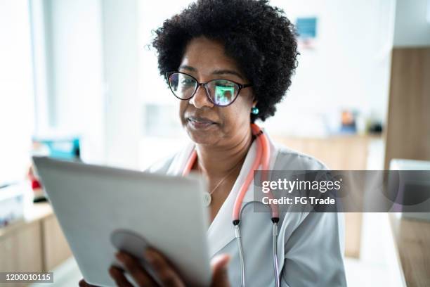 mature female doctor using digital tablet at medical office - electronic medical record stock pictures, royalty-free photos & images