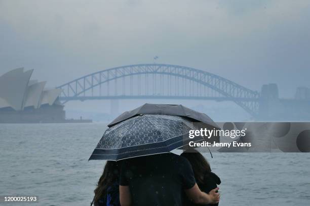 Tourists are seen looking at The Sydney Harbour Bridge in the rain on January 17, 2020 in Sydney, Australia. A severe thunderstorm warning has been...