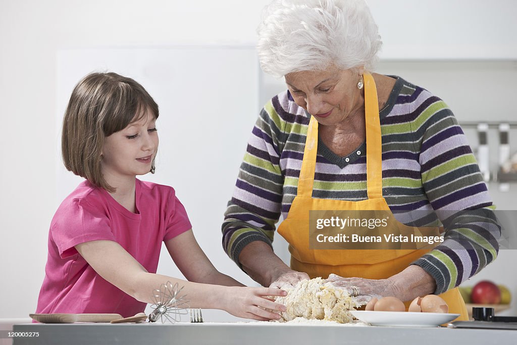 Grandmother teaching granddaughter to make pasta