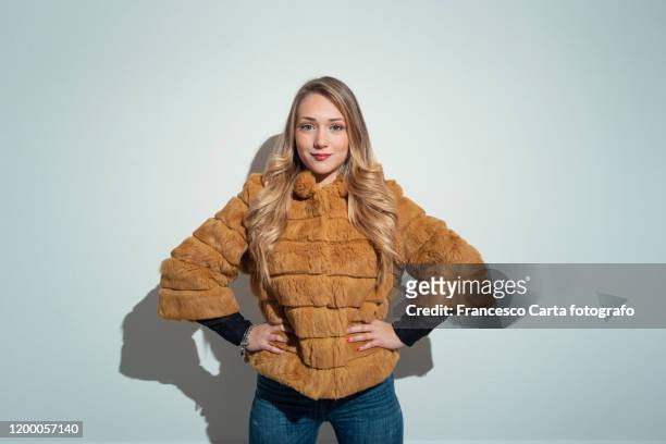 young woman with blonde hair in yellow fur coat - overcoat stock pictures, royalty-free photos & images