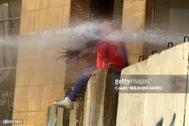 Lebanese Protester is hit with a burst from a water cannon during clashes with army soldiers on February 11 as demonstrators gather in the heart of...