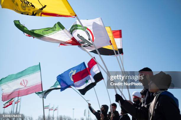 Iranian men hold Iraqi Popular Mobilization Units, Hashd Shaabi , Iran, Iraq, and Islamic Revolutionary Guards Corps flags while taking part a rally...