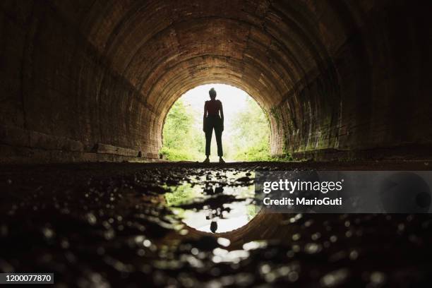 jonge vrouw aan het eind van een tunnel - woman body contour standing stockfoto's en -beelden