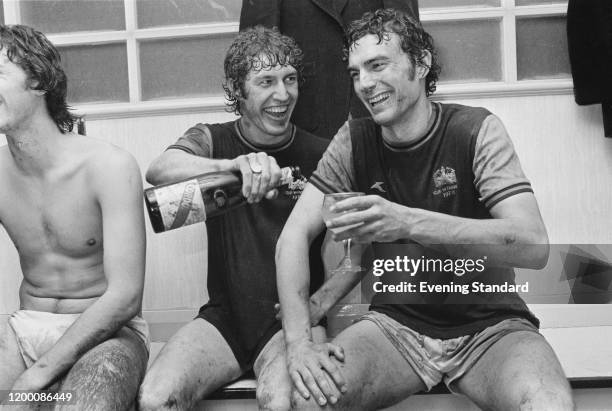 British footballer Pat Holland pouring a glass of champagne for teammate, British footballer Trevor Brooking after West Ham reach the final of the...