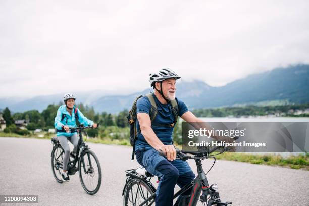 senior couple tourist with bicycles cycling by lake in nature on holiday. - bike riding stock pictures, royalty-free photos & images