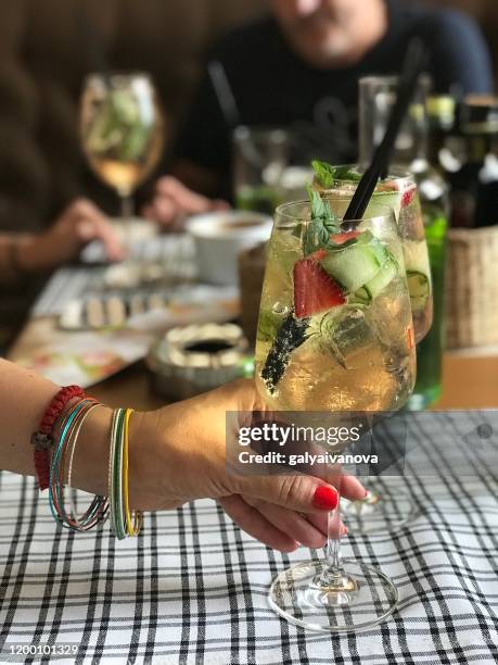 woman sitting at a table holding a cocktail glass - cucumber cocktail stock pictures, royalty-free photos & images