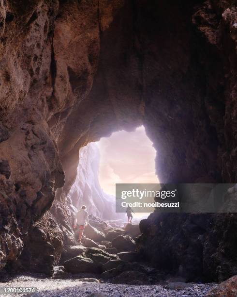 two boys walking through a cave at sunset, laguna beach, california, usa - southern california stock pictures, royalty-free photos & images