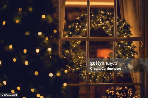 view through a window of a christmas wreath in a living room - celebrate living stockfoto's en -beelden