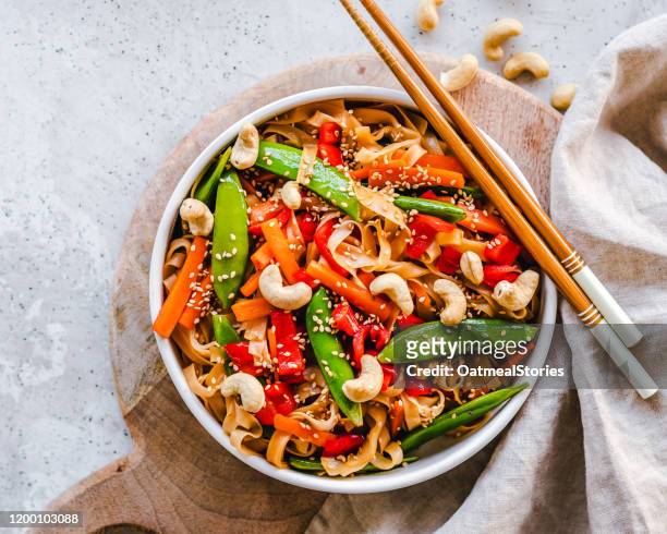 stir fried noodles with mange tout, carrot, red pepper, sesame seeds and cashew nuts - macarrão de arroz imagens e fotografias de stock