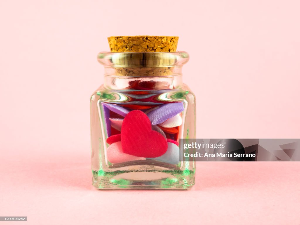 Concept of love and romanticism. A glass jar with colored hearts and a cork stopper