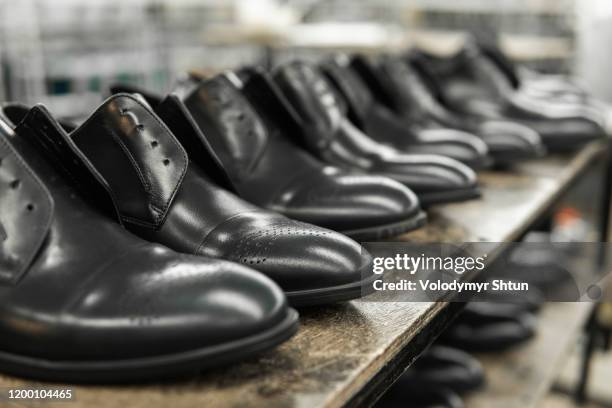 A lot of new black shiny shoes on a shelf. Shoe factory, finished goods warehouse.