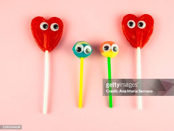 concept of love and family. two red heart lollipops with eyes looking at each other and two smaller lollipops - build presents the family stock pictures, royalty-free photos & images
