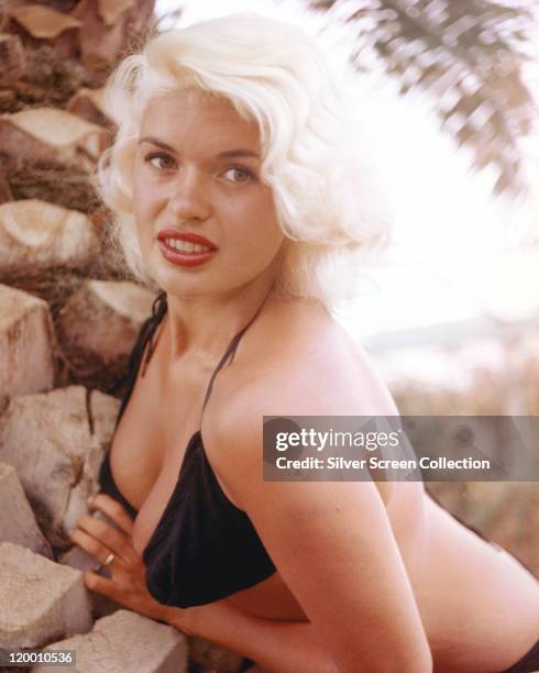 Jayne Mansfield , US actress, wearing a black bikini while posing beside some rocks, circa 1955.