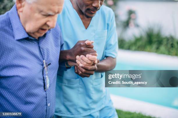 männliche krankenschwester hilft senior mann beim gehen - nurse with old male patient home care stock-fotos und bilder