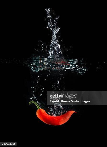 red pepper splashing in water - pepper spray stockfoto's en -beelden