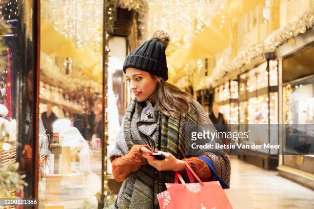woman is window shopping in decorated street. - holiday 2019 stock pictures, royalty-free photos & images