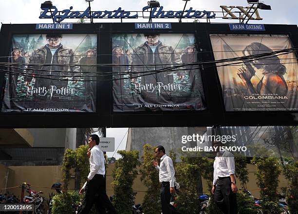Indonesians walk past posters of Harry Potter movie in Jakarta on July 29, 2011 which simultaneously play at two cinema halls in one theater....