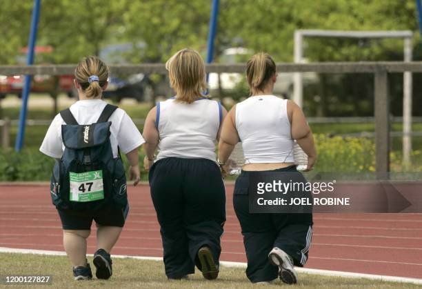 Trois personnes de petite taille se dirigent, le 02 juillet 2005 vers la piste d'athlétisme du stade de Montigny-le-Bretonneux, lors des IVe Jeux...